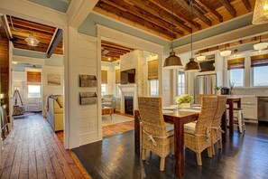 A spacious living area with a fireplace, dining table, and wicker chairs.