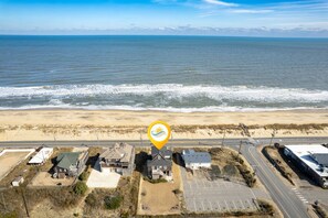 An aerial view of a coastal area with houses, a road, and a beach.