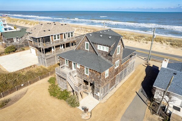 A beachfront house with a two-story structure, a balcony, and a view of the ocean.