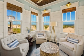A room with three beige armchairs, a round coffee table, and a floor lamp.