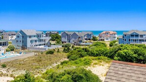 A coastal residential area with houses, a swimming pool, and a clear view of the ocean. - La Ballena Cottage Dog Friendly Pool Ocean Views (Corolla)