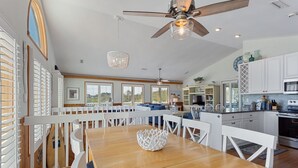 A spacious kitchen with white cabinetry, a wooden dining table, and a ceiling fan. - La Ballena Cottage Dog Friendly Pool Ocean Views (Corolla)
