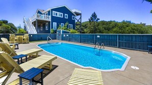 A swimming pool with lounge chairs, a deck, and a two-story building with a balcony. - La Ballena Cottage Dog Friendly Pool Ocean Views (Corolla)
