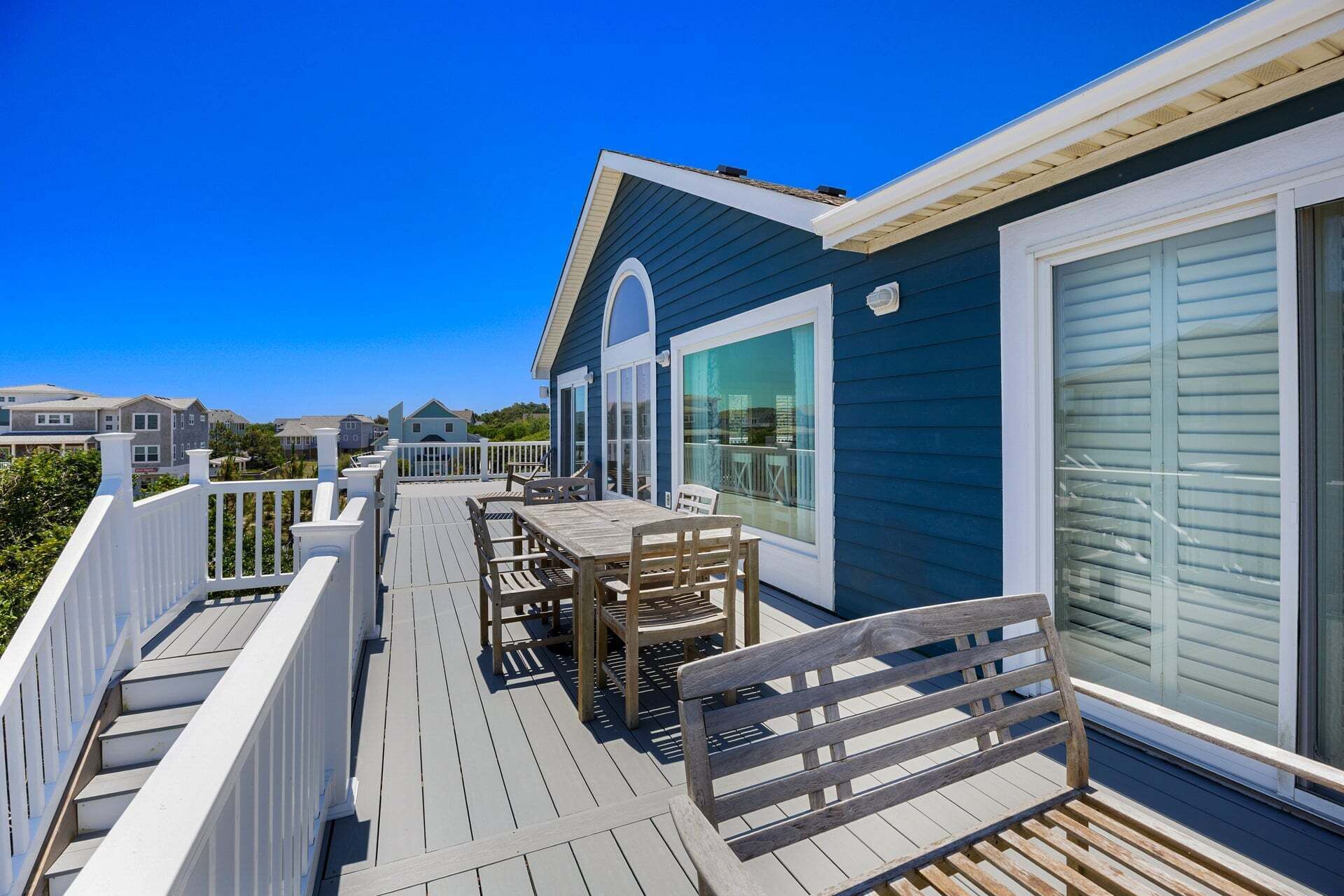 A deck with outdoor furniture, a railing, and a view of neighboring houses.