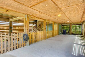 A spacious indoor area with a concrete floor, wooden beams, and a wooden fence.