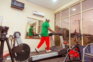 A gym with a treadmill, stationary bike, and weight bench. - Hotel Reno (Abuja)