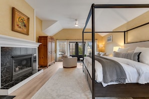 A bedroom with a four-poster bed, a fireplace, and a view of the outdoors. - Claire King Suite in Carriage House - Red Clover Inn (Mendon)