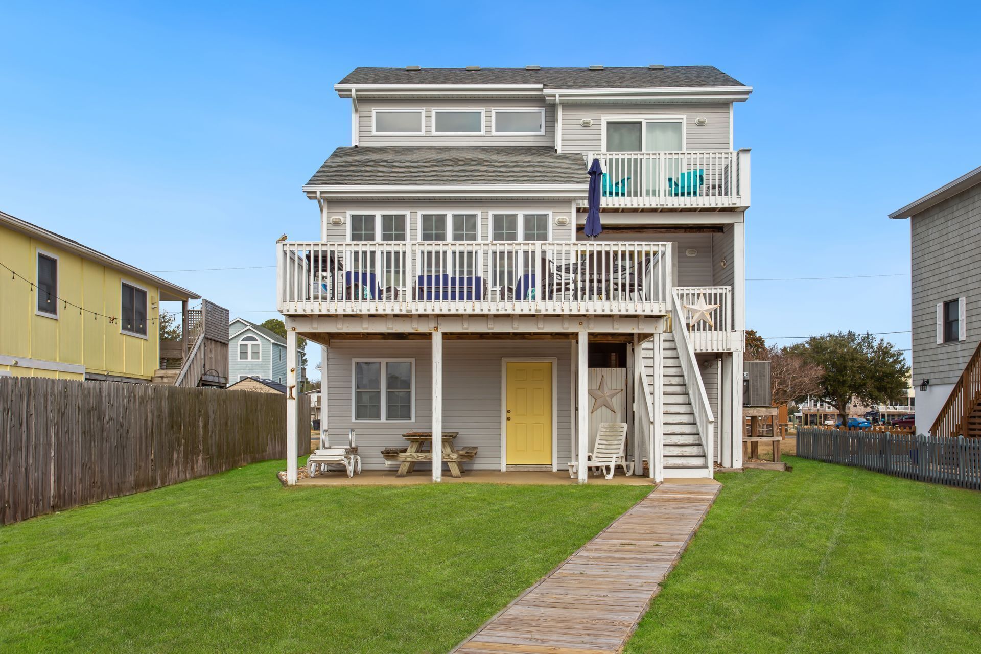 A two-story house with a balcony, a front door, and a wooden deck leading to the entrance.