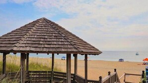 A wooden gazebo on a beach with a clear view of the ocean and a boat in the distance. - 6140 Spindrift * On the Golf Course (Nags Head)