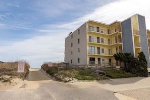 A multi-story building with balconies, a beach driving permit sign, and a speed limit sign. - Beachfront OBX condo: family fun & ocean views (Nags Head)