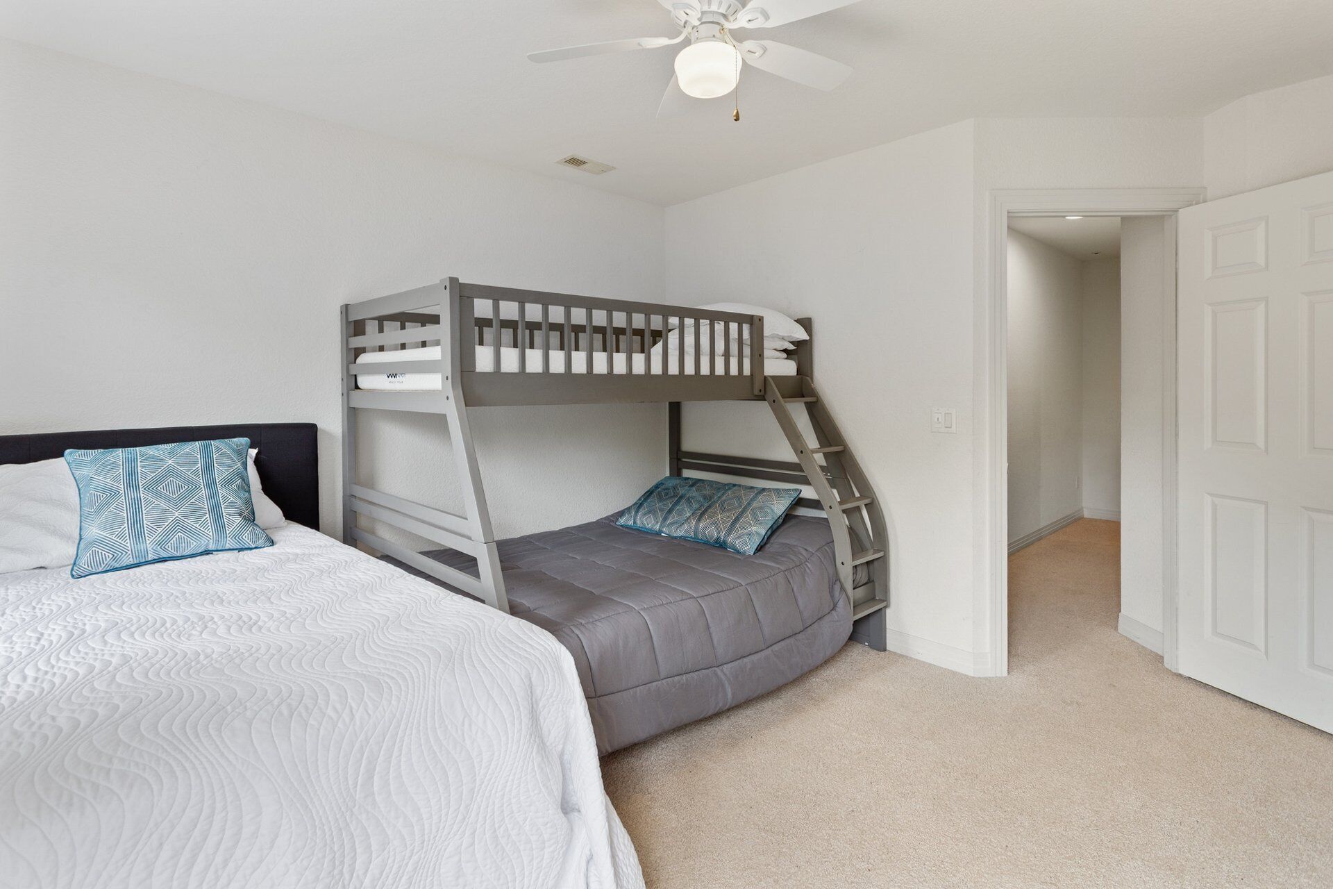 A bedroom with a bunk bed, a single bed, and a ceiling fan.
