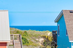 A coastal view with a wooden deck and a house with a blue exterior.