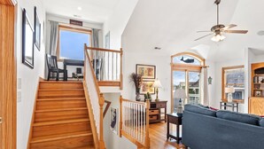 Un espacio habitable amplio con una escalera de madera, un ventilador de techo y vistas al exterior.
