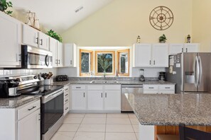 Enjoy cooking in this well-equipped kitchen with a refrigerator, oven, and microwave, and take in the view of lush greenery from the window.