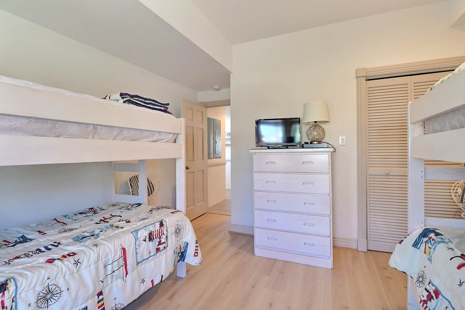 A bedroom with bunk beds, a dresser, and a television on top.