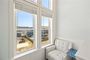 Quarto com vista para uma área residencial, um radiador branco e uma pequena mesa.