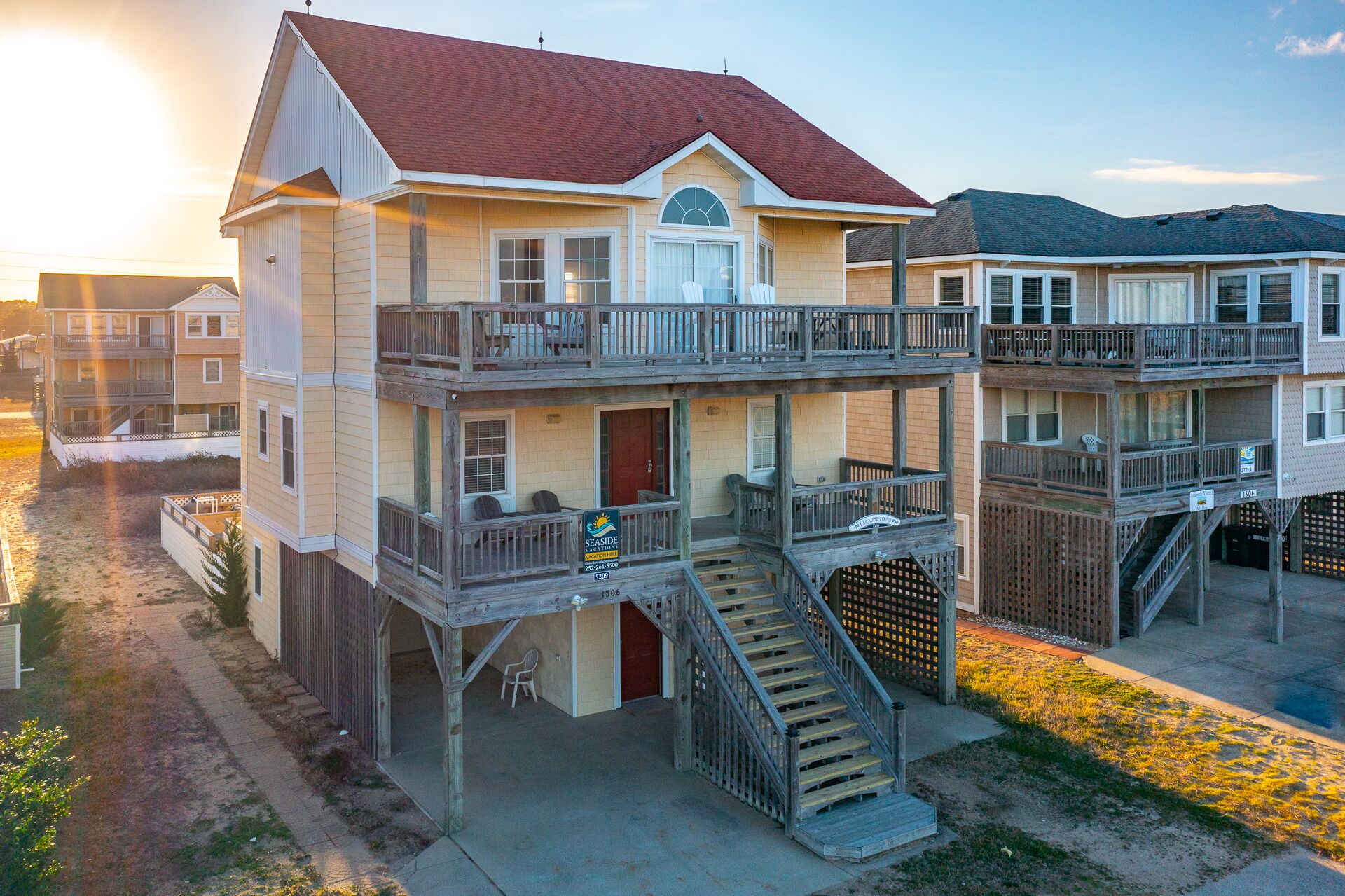 A multi-story beachfront property with balconies, a covered patio, and a staircase leading to the upper levels.