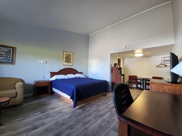 A hotel room with a bed, a desk, a chair, a sofa, and a TV. - Welcome Inn and Suites (St. Johns)
