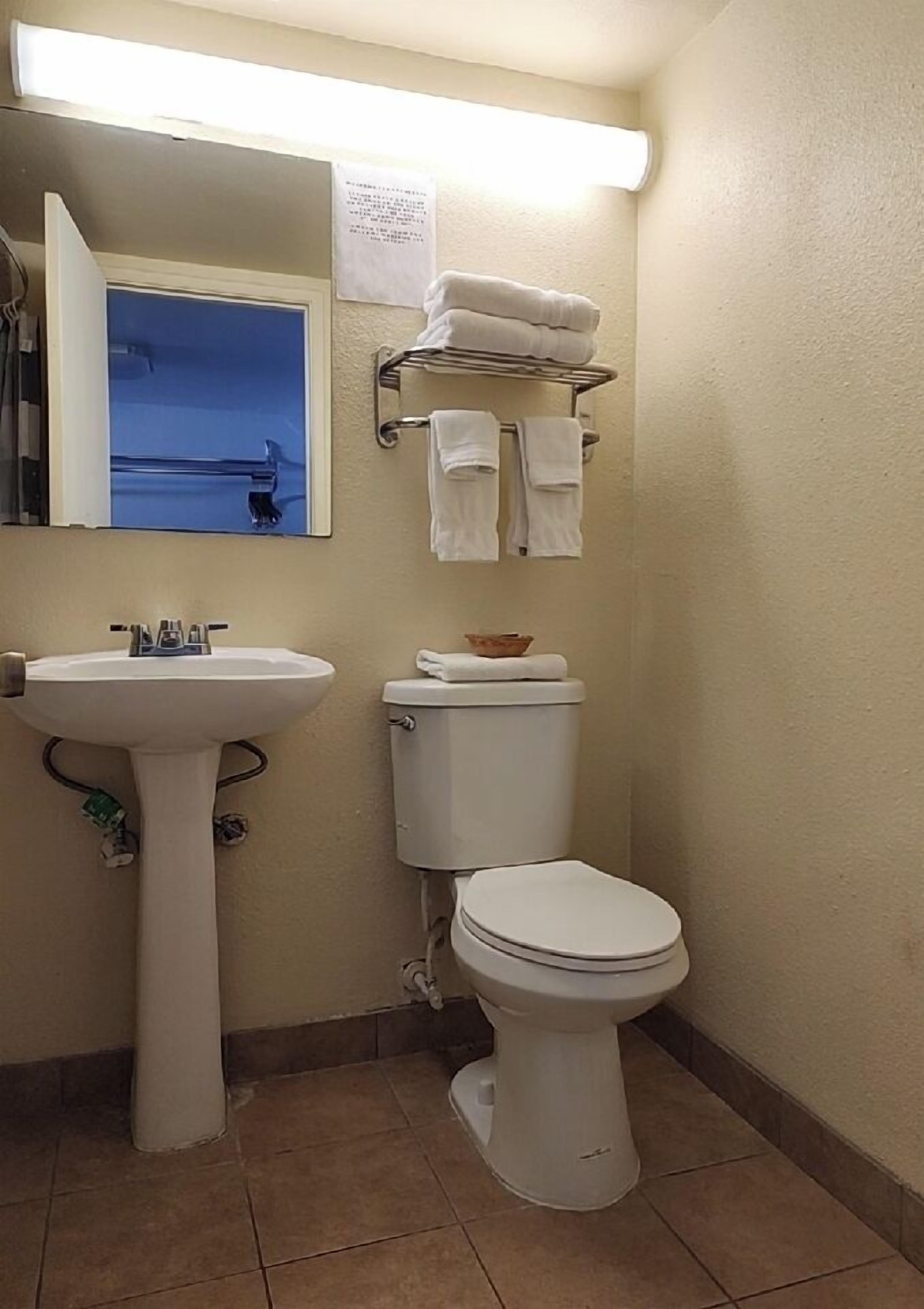 A bathroom with a sink, toilet, and towel rack.