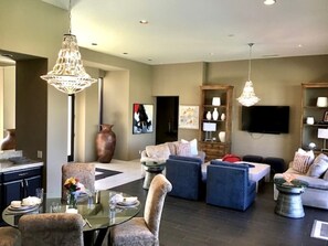 A modern living room with a glass dining table, sofas, and a TV.