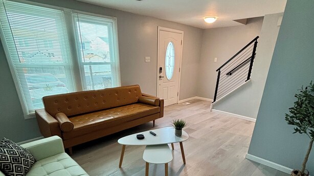 A living room with a brown sofa, a white sofa, a small white table, and a ceiling fan. - Modern & Recently Renovated Beach house. Sleeps 6 (Brigantine)