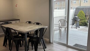 A dining area with a table and chairs, a ceiling fan, and a view of the outside through a sliding glass door. - Modern & Recently Renovated Beach house. Sleeps 6 (Brigantine)