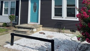 A two-story building with a blue door, white-framed windows, and a gravel driveway. - Modern & Recently Renovated Beach house. Sleeps 6 (Brigantine)