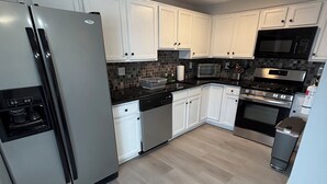 A modern kitchen with white cabinets, stainless steel appliances, and a tiled backsplash. - Modern & Recently Renovated Beach house. Sleeps 6 (Brigantine)