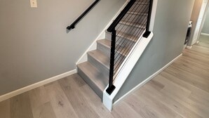 A staircase with a black handrail and white steps, leading to a landing with a light switch and vent. - Modern & Recently Renovated Beach house. Sleeps 6 (Brigantine)