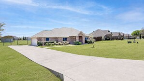 A residential neighborhood with houses, a concrete driveway, and well-maintained lawns. - Perfect Stay in Ranch-like House with Huge Backyard! (Forney)