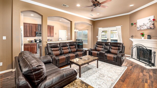 A spacious living room with leather sofas, a coffee table, and a fireplace. - Perfect Stay in Ranch-like House with Huge Backyard! (Forney)