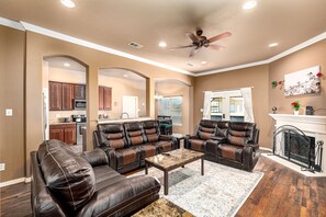A spacious living room with leather sofas, a coffee table, and a fireplace.