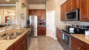 A kitchen with granite countertops, stainless steel appliances, wooden cabinets, and a white door. - Perfect Stay in Ranch-like House with Huge Backyard! (Forney)