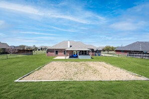 A residential property with a fenced backyard, a covered patio, and a brick house.