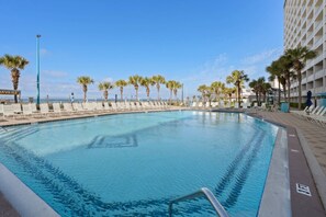 Relax by the pool surrounded by palm trees and lounge chairs.
