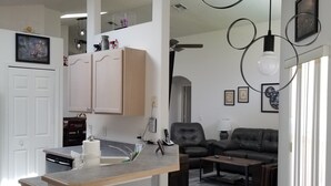 Een moderne keuken met een centraal eiland, een eethoek met een bank en salontafel, en een woonkamer met een open haard.