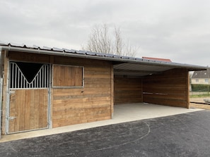A wooden stable with a metal roof, a gated entrance, and a concrete floor. - Comfortable single-storey house 100 m2 on a fenced plot (Noyelles-sur-Mer)