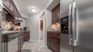 Una cocina moderna con electrodomésticos de acero inoxidable, armarios de madera oscura y salpicadero de azulejos.