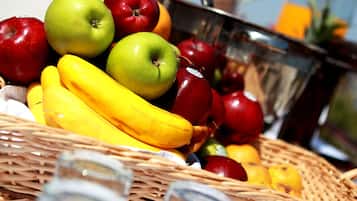 Un panier de fruits contenant des bananes, des pommes et des oranges, posé sur une table.