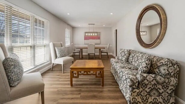 Un salon avec une table basse en bois, un canapé à motifs et un coin repas comprenant une table et des chaises.