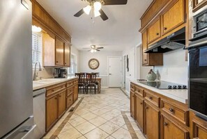 Una cocina con armarios de madera, un refrigerador, una estufa y un ventilador de techo.