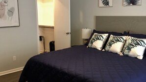 Une chambre à coucher comprenant un lit, une table de chevet, une lampe et une porte donnant sur une salle de bain.