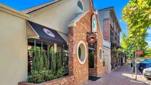 A building with a brick facade, circular windows, and a sign with a logo.