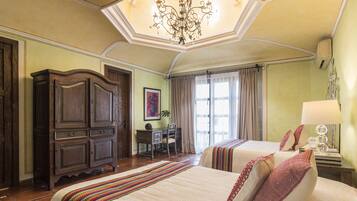 Ein Hotelzimmer mit zwei Betten, einem Schreibtisch, einem Sessel und einer Chandelier.