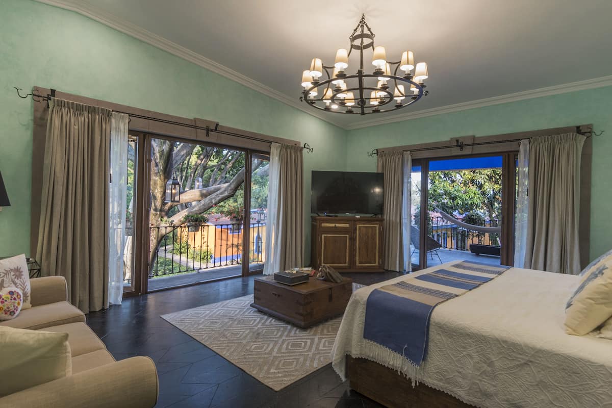 A spacious bedroom with a large bed, a television, and a view of a balcony.