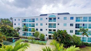 A multi-story hotel with a central courtyard, surrounded by lush greenery and palm trees. - Palm Village Acqua (Ipojuca)