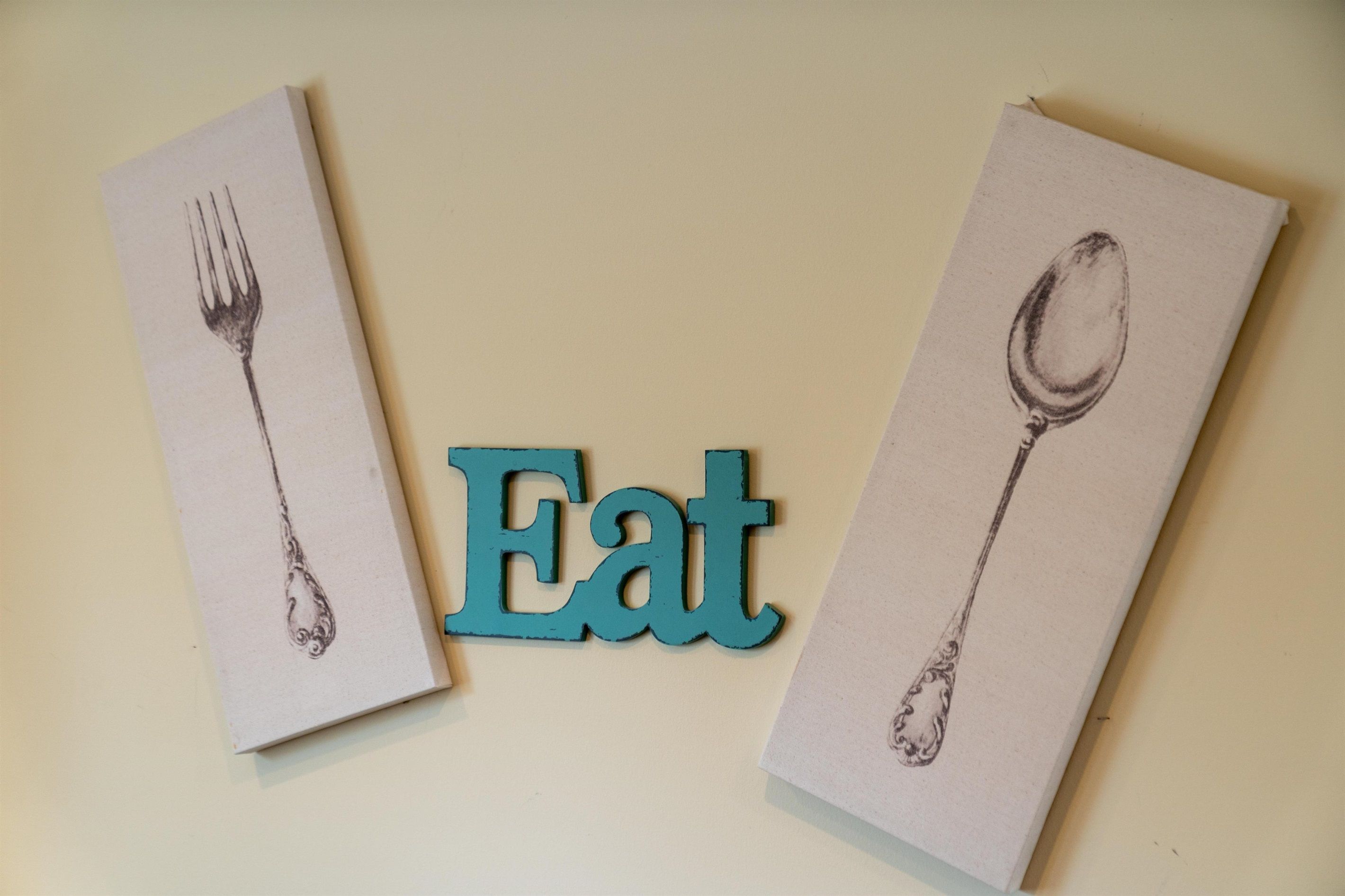 Deux serviettes en papier ornées de dessins d’ustensiles et un panneau bleu avec le mot « Manger ».