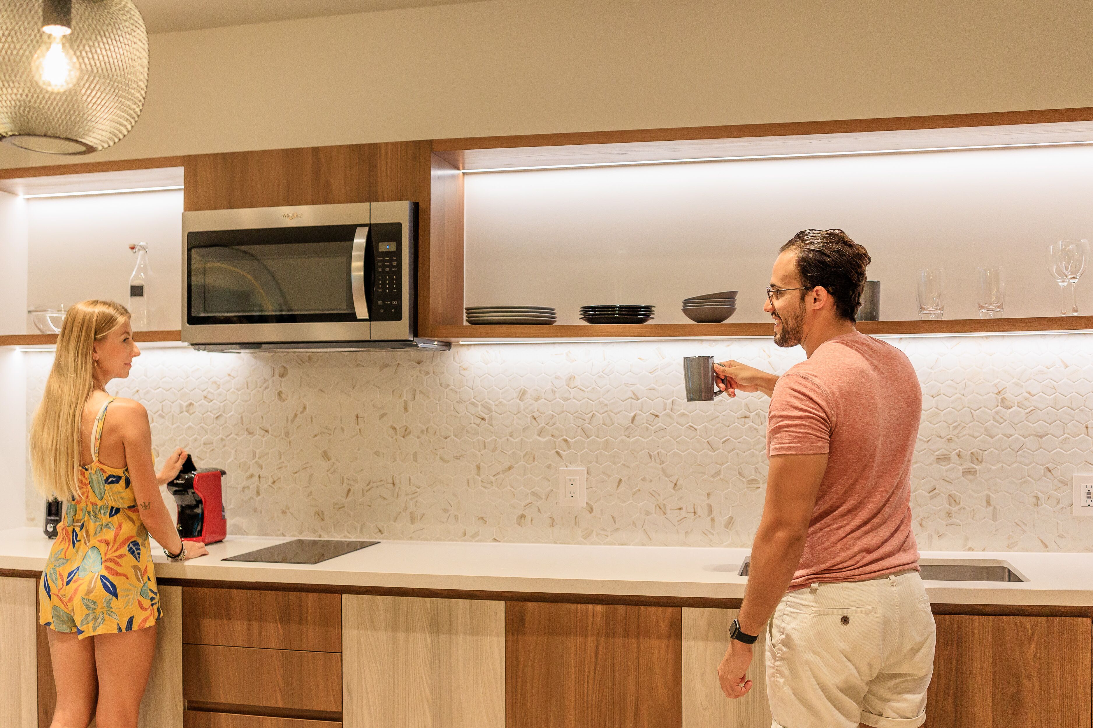 A modern kitchen with wooden cabinets, a stainless steel microwave, and a countertop with a coffee maker.
