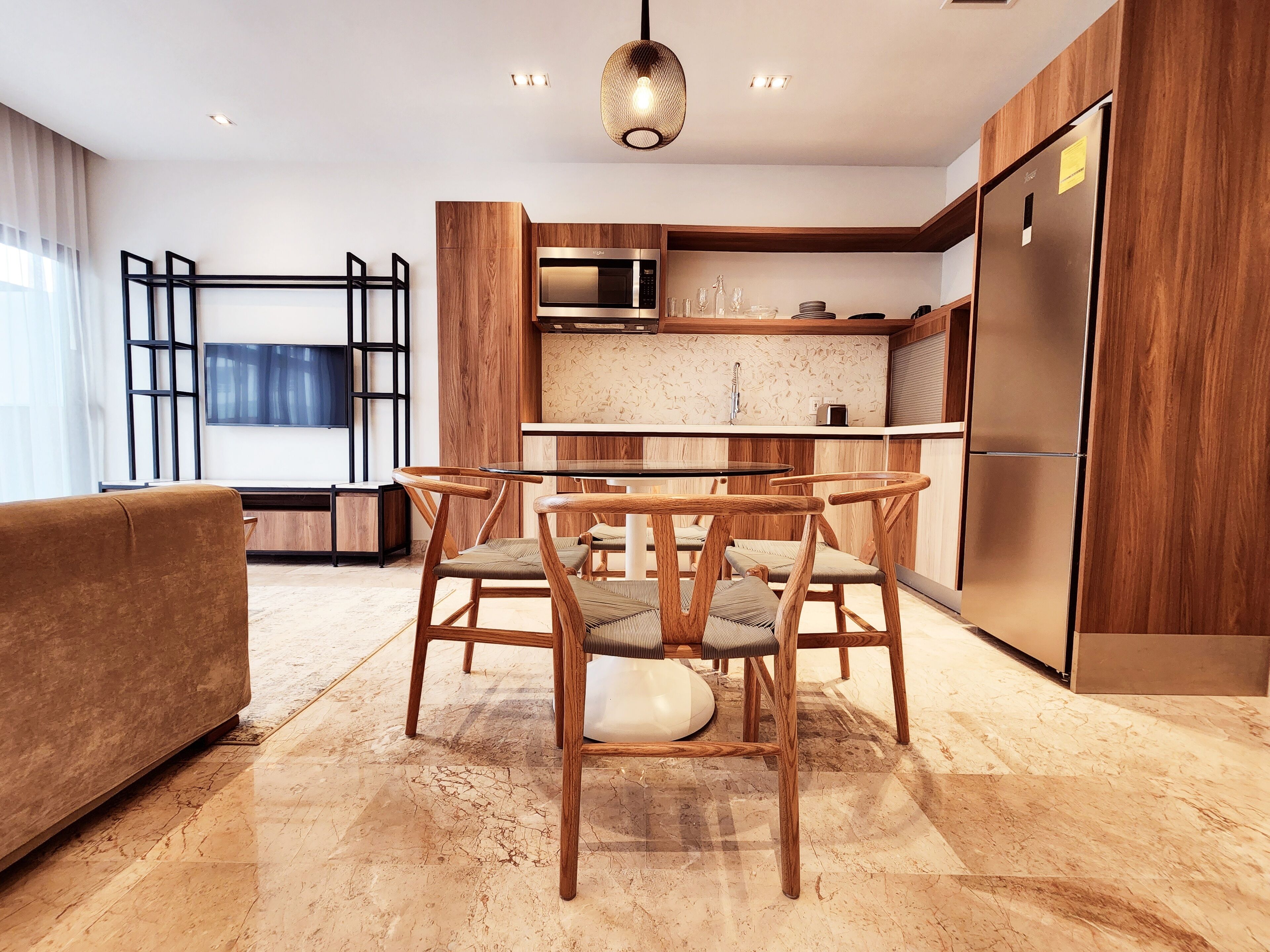 Una cocina moderna con armarios de madera, un microondas integrado y un refrigerador de acero inoxidable.