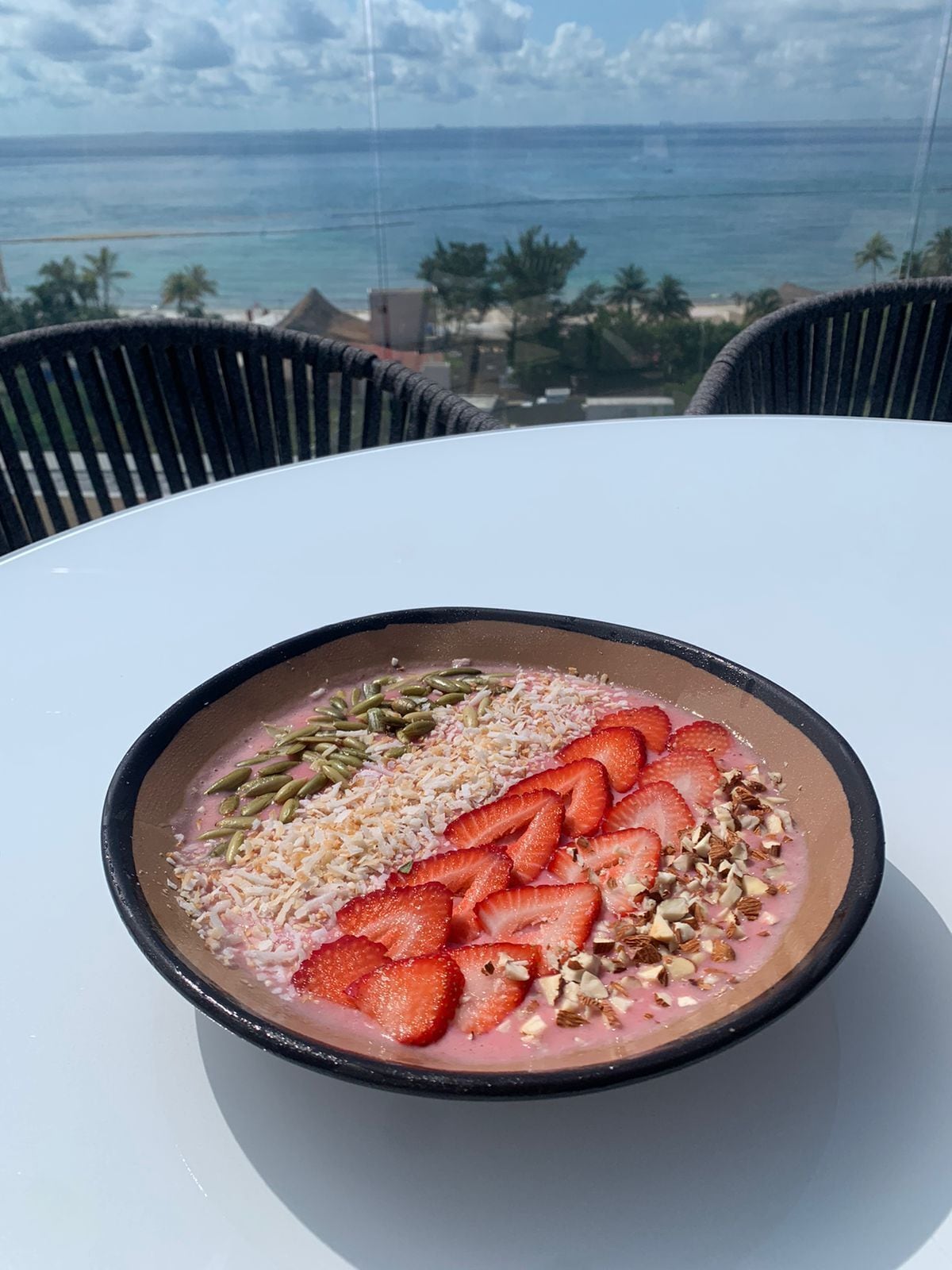 A bowl of food on a table with a view of the ocean.